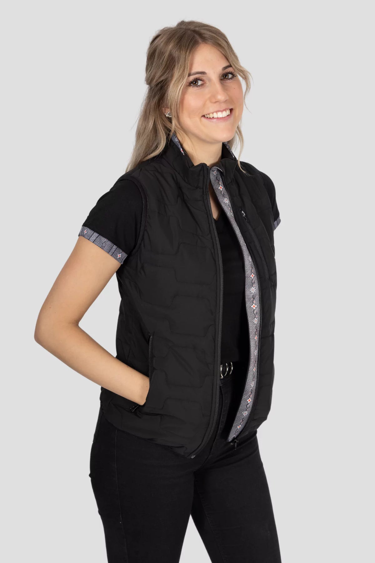 Gilet Edelweiss Damen in Schwarz mit grauem Edelweiss-Muster, hochwertig verarbeitet, mit dezenten Edelweiss-Streifen am Reissverschluss und Nacken, ideal für Freizeit, Arbeit und elegante Anlässe