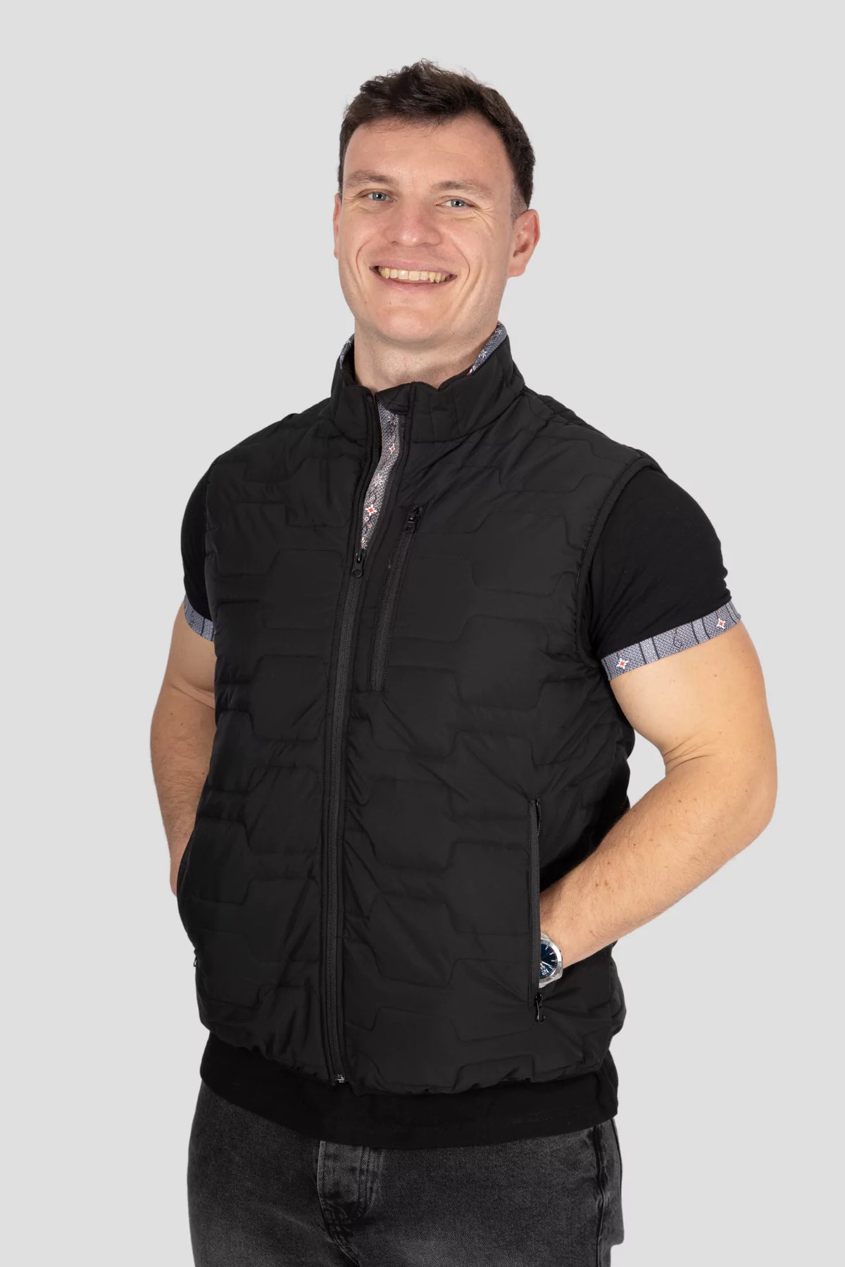 Gilet Edelweiss Herren in Schwarz mit grauem Edelweiss-Muster, hochwertig verarbeitet, mit dezenten Edelweiss-Streifen am Reissverschluss und Nacken, ideal für Arbeit, Freizeit und elegante Anlässe.