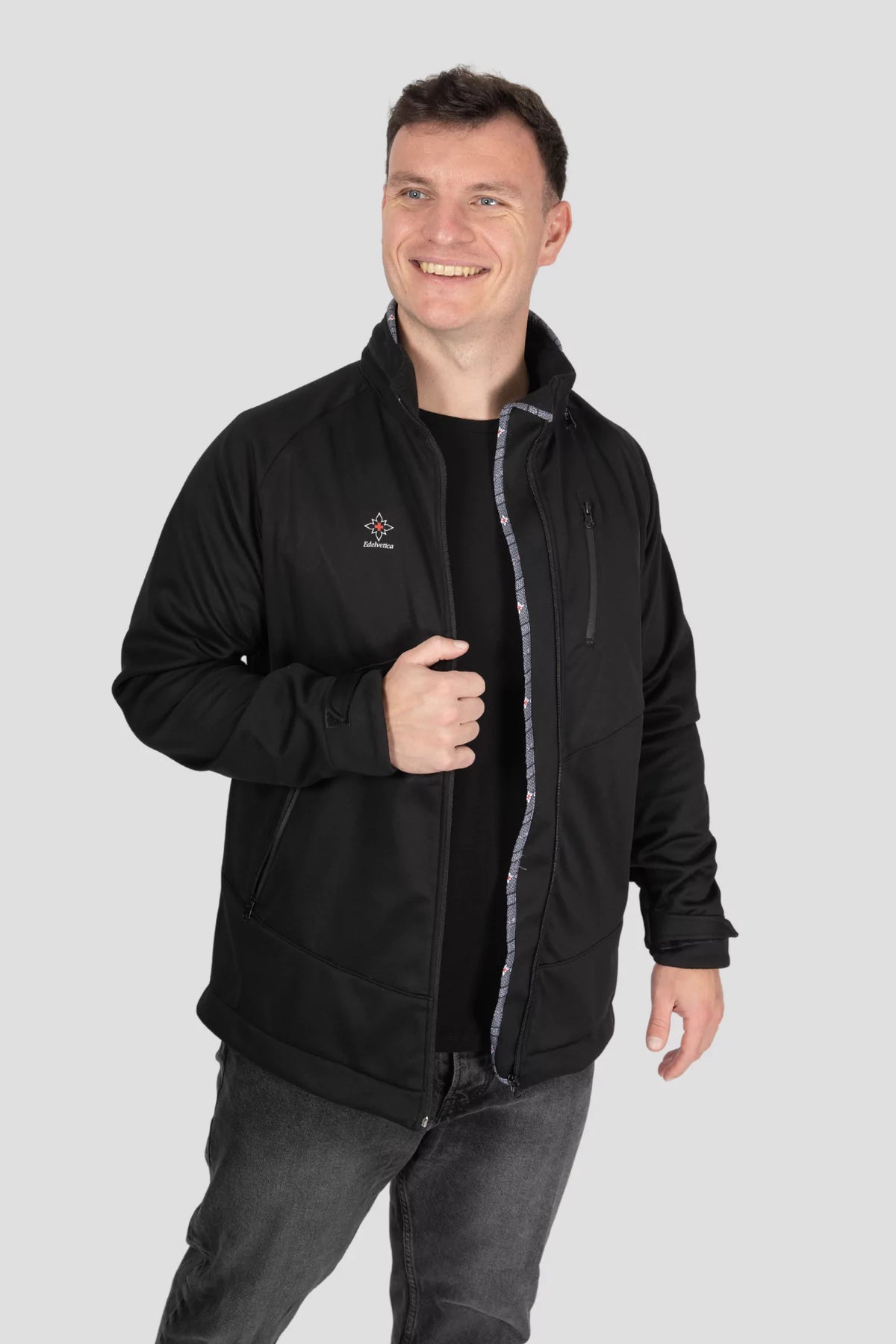 Softshell Jacke Edelweiss Herren von Edelvetica, schwarze Outdoor-Jacke mit grauem Edelweiss-Muster, wasserdicht und winddicht, mit Kapuze und hochwertigem Design.